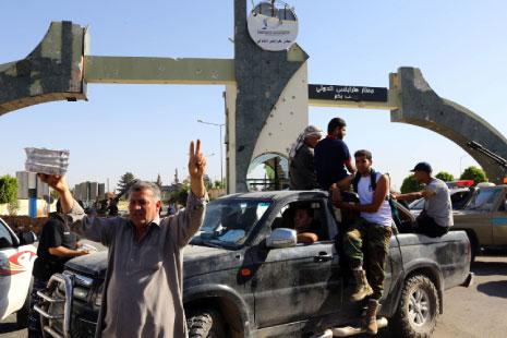 مقاتلون من «فجر ليبيا» يحتفلون أمام مدخل مطار طرابلس بعد السيطرة عليه (أ ف ب) 