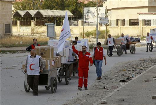 عناصر من الهلال الاحمر السوري ينقلون مساعدات الى حي بستان القصر في حلب الذي يسيطر عليه المسلحون، امس (رويترز)