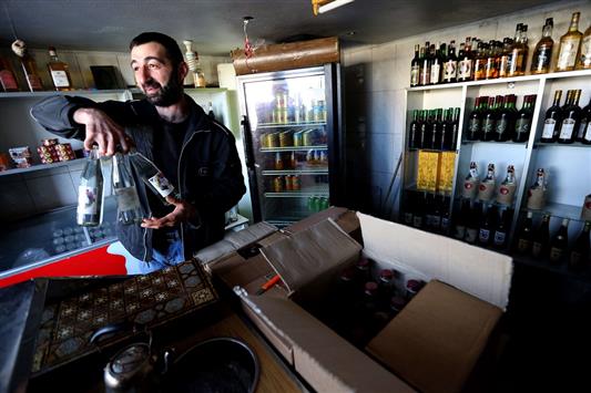 تاجر سوري يحمل زجاجات عرق "الميماس" في متجره في حمص (أ ف ب)