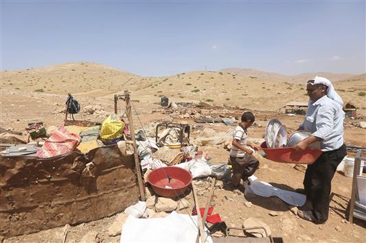 فلسطيني ونجله يجمعان اغراضهما بعد تدمير الاحتلال خيمة العائلة في الضفة الغربية امس (ا ف ب)