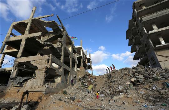 اطفال فلسطينيون يمرون بين مبان مدمرة في غزة امس (ا ف ب)