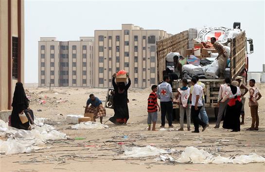 يمنيون يتسلمون مساعدات من الهلال الأحمر اليمني في عدن (أ ف ب)