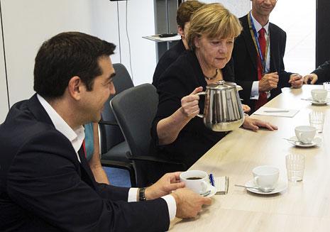 ميركل تسكب الشاي لرئيس الحكومة اليونانية قبل القمة أمس (أ ف ب)