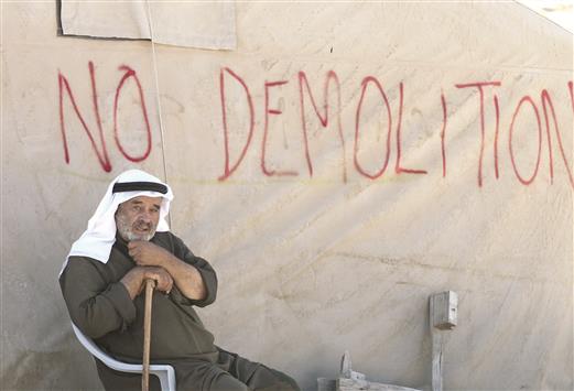 فلسطيني يجلس أمام خيمة كتب عليها «لا للهدم» في الضفة الغربية أمس (ا ف ب)