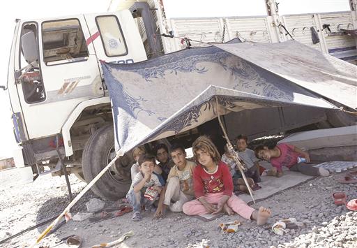 أطفال سوريون من تل أبيض في خيمة على الحدود التركية (رويترز)