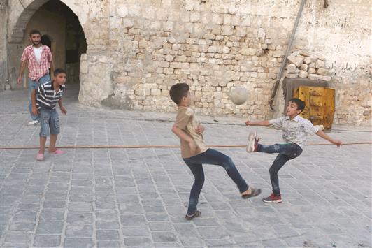 أطفال يلعبون كرة القدم في حلب أمس الأول (رويترز)