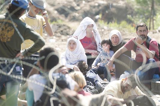 مهاجرون سوريون ينتظرون عبور الحدود بين اليونان ومقدونيا، أمس (أ ف ب)