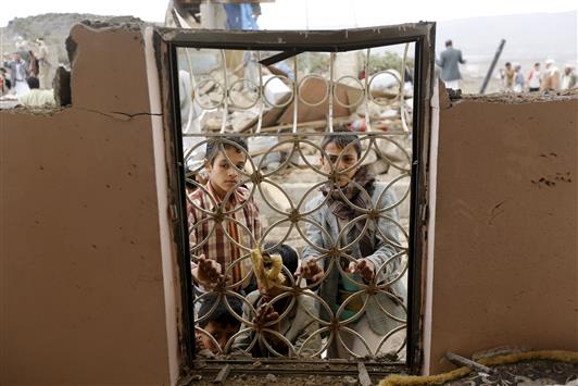 صِبية خلف نافذة منزل دمرته غارة سعودية في اليمن (رويترز)