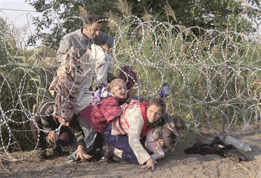لاجئون سوريون يجتازون شريطاً شائكاً على الحدود الصربية المجرية، امس (رويترز)