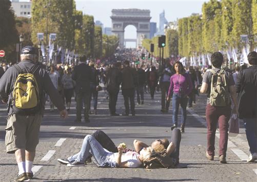 ثنائي يتمدد على الأرض في الشانزليزيه في باريس، أمس (رويترز)