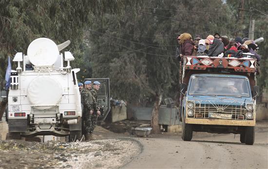 شاحنة تقل مزارعين تمر من أمام عناصر الـ«يونيفيل» في بلدة الوزاني الحدودية أمس (رويترز)