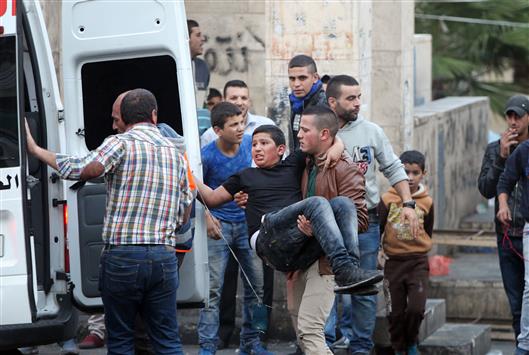 شاب يحمل مصاباً برصاص الاحتلال الاسرائيلي في الخليل في الضفة الغربية المحتلة امس (ا ف ب)