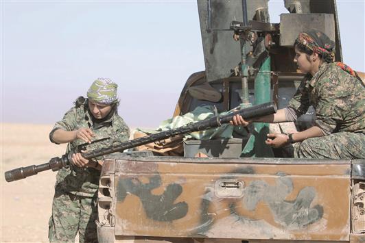 كرديتان تعدان السلاح خلال المعارك مع «داعش» في رأس العين (رويترز)