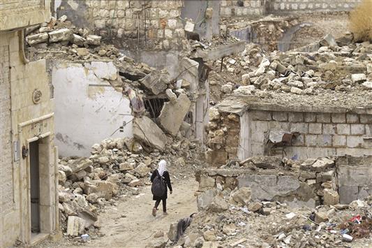تلميذة تسير وسط مبان مدمرة في معرة النعمان في ريف ادلب امس (رويترز)