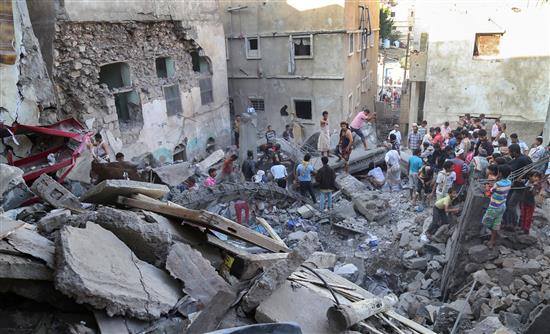 يمنيون يقفون أمام الدمار الذي خلفه القصف السعودي على منازلهم في تعز أمس (أمس)