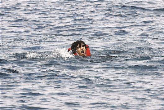 لاجئ سوري يطلب مساعدة خلال محاولته الوصول الى الشاطئ في اليونان امس (رويترز)