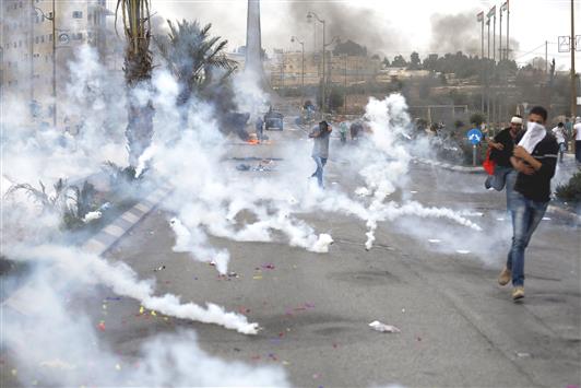 قنابل الاحتلال المسيلة للدموع تنهمر على الفلسطينيين خلال مواجهات في البيرة شمال رام الله، أمس (أ ف ب)