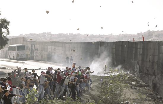 شبان فلسطينيون يرشقون قوات الاحتلال بالحجارة قرب أبو ديس في الضفة الغربية المحتلة أمس (ا ف ب)