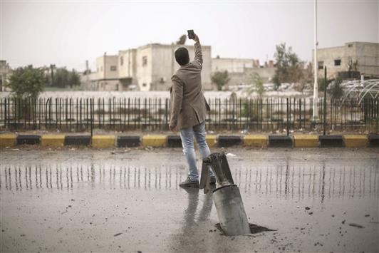 شاب يلتقط «سيلفي» وخلفه صاروخ غير منفجر في دوما امس (ا ب ا)