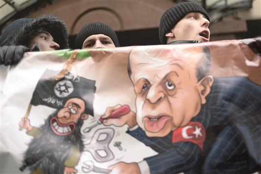 متظاهرون روس يحملون رسماً كاريكاتورياً لأردوغان خلال تظاهرة أمام السفارة التركية في موسكو، أمس (أ ف ب)