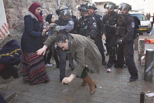 شرطي إسرائيلي يهاجم امرأة فلسطينية في القدس المحتلة، أمس (أ ف ب)