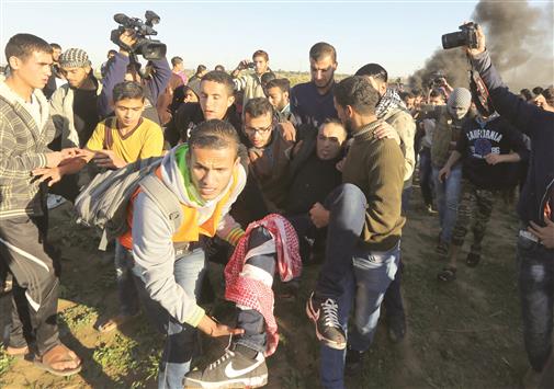 فلسطينيون ينقلون جريحاً اصيب برصاص قوات الاحتلال الاسرائيلي على الحدود مع غزة امس (ا ف ب)