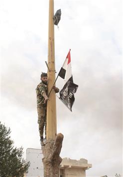 جندي سوري ينزل علم «داعش» ويرفع مكانه العلم السوري في المحطة الحرارية في حلب أمس الأول (ا ف ب)