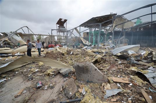 عمّال يتفقّدون الدمار اللاحق بمصنع للخشب في الحديدة جراء قصفه بغارة جوية، أمس (رويترز)