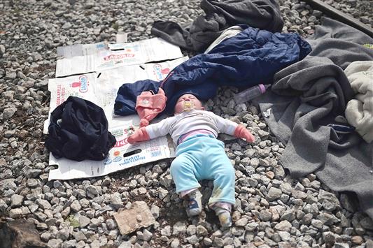  طفل ينام قرب خط القطار على الحدود اليونانية المقدونية امس (ا ف ب)