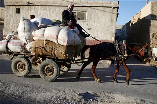 رجل على عربة يجرها حصان في دوما في غوطة دمشق أمس (رويترز)