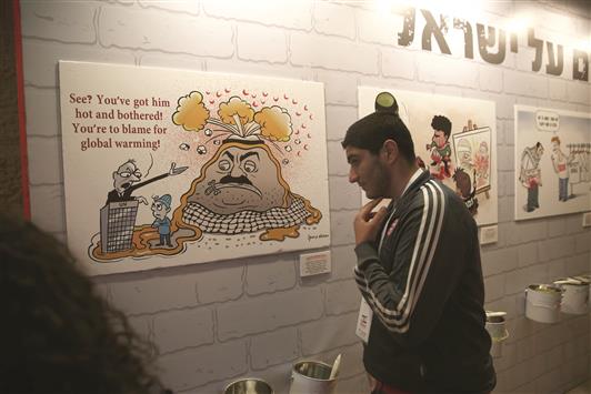 مستوطن ينظر الى كاريكاتير ضد المقاطعة في القدس المحتلة امس (ا ف ب)