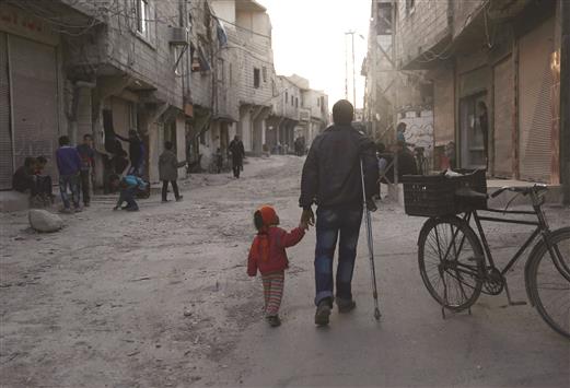 رجل يسير مع طفلته في برزة في دمشق امس (ا ف ب)