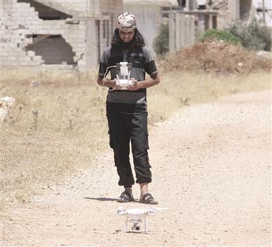 مسلح يحمل طائرة من دون طيار في بلدة تلبيسة في حمص (أ ف ب)