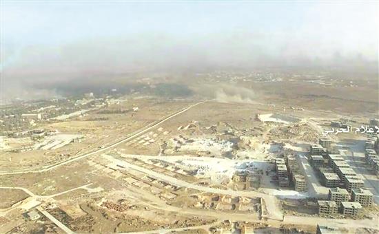 مشهد عام لساحة المعركة والمشروع السكني «1070» الذي انطلق المسلحون من أطرافه للهجوم على سور كلية المدفعية (الى يسار الصورة) (الاعلام الحربي)