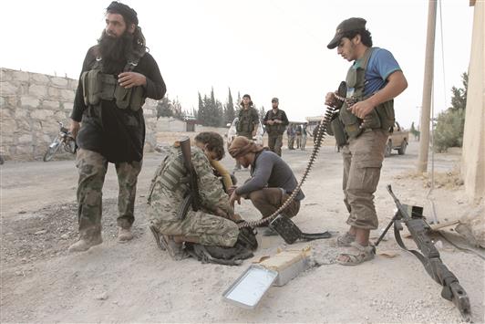 مسلحون يعيدون تذخير أسلحتهم خلال وجودهم في كلية المدفعية في حلب (رويترز)