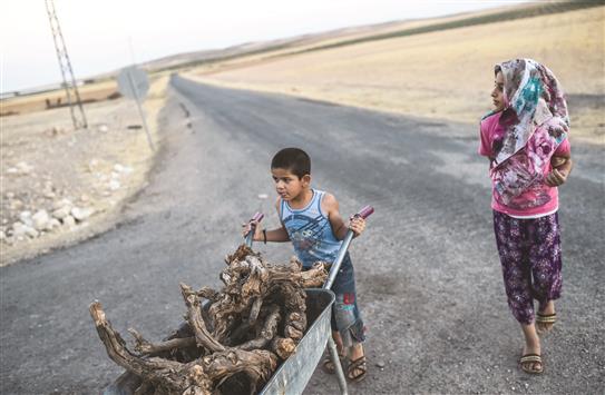 طفل يدفع عربة يدوية وإلى جانبه فتاة في بلدة قرقميش على الحدود السورية التركية امس الاول (أ ف ب)