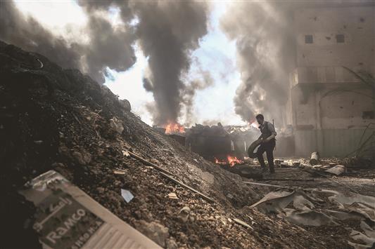 مقاتل من «جيش الإسلام» يرمي إطاراً فوق النار للتعمية على الطائرات الحربية السورية في دوما أمس الاول (أ ف ب)