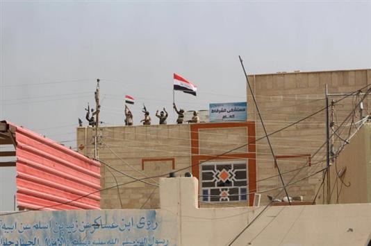 جنود عراقيون يرفعون العلم العراقي فوق المباني في قضاء الشرقاط (عن الإنترنت)