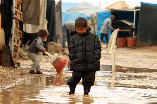 طفل سوري يلهو بالوحل في مخيم باب السلامة للنازحين قرب مدينة أعزاز عند الحدود مع تركيا أمس (أ ف ب)