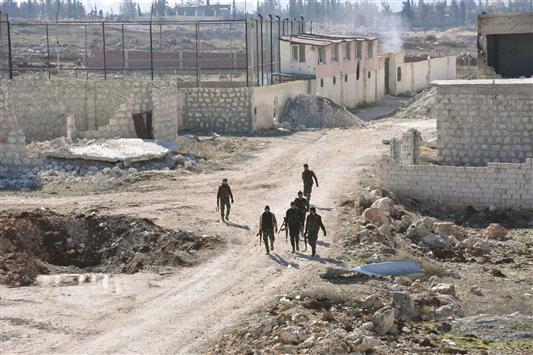 مُقاتلون مُوالون للحكومة السورية يمرّون وسط الدمار في حي بعيدين في ريف حلب الشرقي، أمس (ا ف ب)