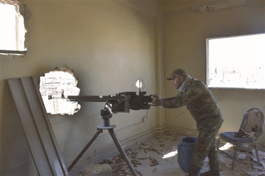 مقاتل موالٍ للجيش السوري يصوّب سلاحه من داخل منزل مدمّر خلال عملية تقدّم القوات في حي بعيدين في حلب الشرقية أمس (أ ف ب)