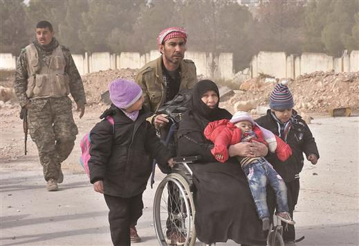 جندي سوري يساعد عائلة من حي جبل بدرو المحرر اثناء نزوحها باتجاه الاحياء الغربية لمدينة حلب أمس (أ ف ب)