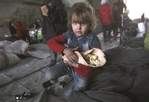 طفلة هربت مع عائلتها من مناطق سيطرة المسلحين تحمل طعاماً في مركز ايواء في حي جبرين شرق حلب أمس (أ ف ب)