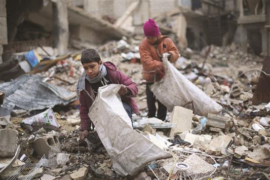طفلان سوريان يجمعان الحطب من ركام الأبنية لاستخدامه في التدفئة والطبخ في الزملكة أمس (ا ف ب)