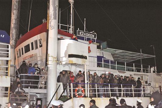 عناصر من الشرطة الايطالية يراقبون مهاجرين على متن السفينة «عز الدين» في ميناء كوريليانو كالابرو امس الاول (ا ب ا)