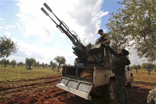 مسلحان يعدان مضاداً للطائرات خلال الاشتباكات مع الجيش السوري في رتيان في ريف حلب أمس (رويترز)