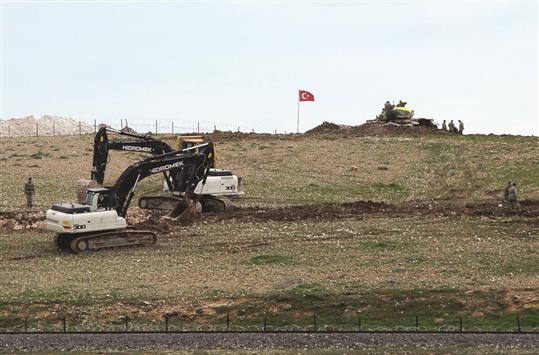 آليتان تعملان، بحماية دبابة تركية، على تمهيد الارض في قرية أشمة السورية لبناء ضريح سليمان شاه امس (رويترز)