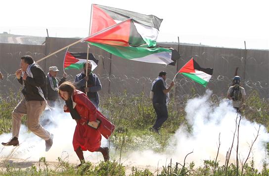 فلسطينيون يحملون علم بلادهم خلال مواجهات مع قوات الاحتلال في الضفة الغربية المحتلة أمس (أ ف ب)