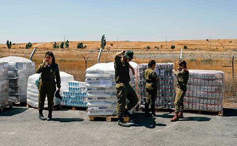 جنود إسرائيليون إلى جانب «مساعدات» سوف تنقل «لمساعدة لاجئين سوريين» (أ ف ب)