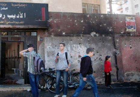 تلاميذ امام مدرستهم بعد يوم على استهداف حي المحطة في حمص بقذائف الهاون (أ ف ب) 